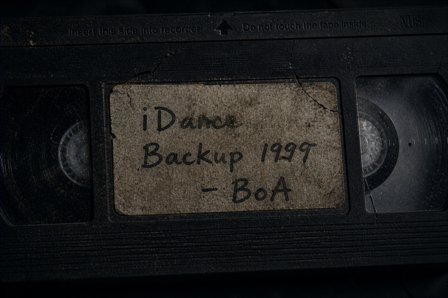 Close-up of a decaying analog storage medium labeled iDance 1999 BoA showing digital decay.