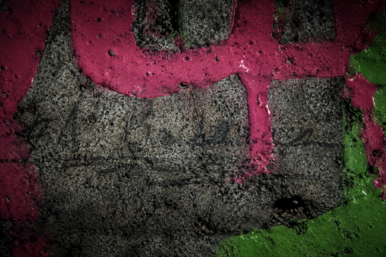 Macro detail of neon paint permanently destroying historical textures on concrete.