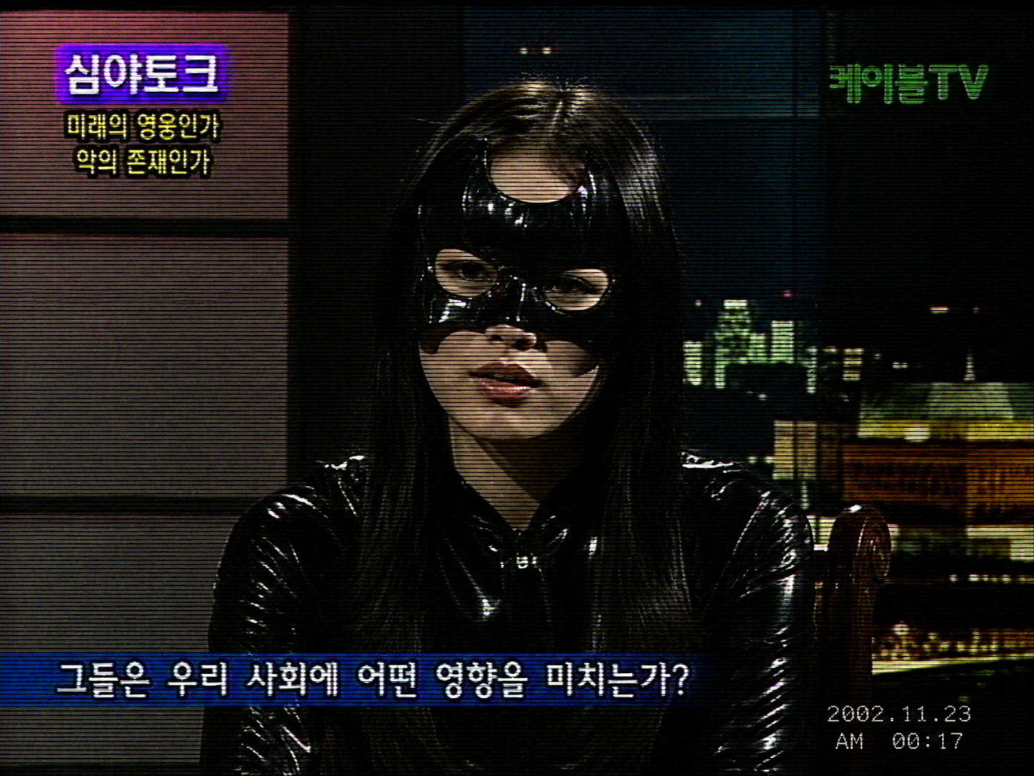 Low-resolution 2007 South Korean cable television screen capture of an unidentified woman in a Catwoman costume inside a dark studio broadcast.