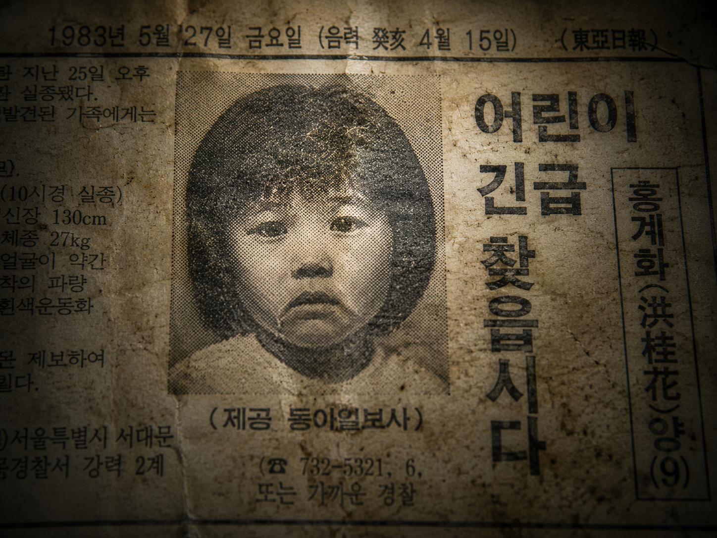 Macro detailed view of a coarse halftone black-and-white portrait of a child inside an aged, yellowed 1983 South Korean newspaper clipping.