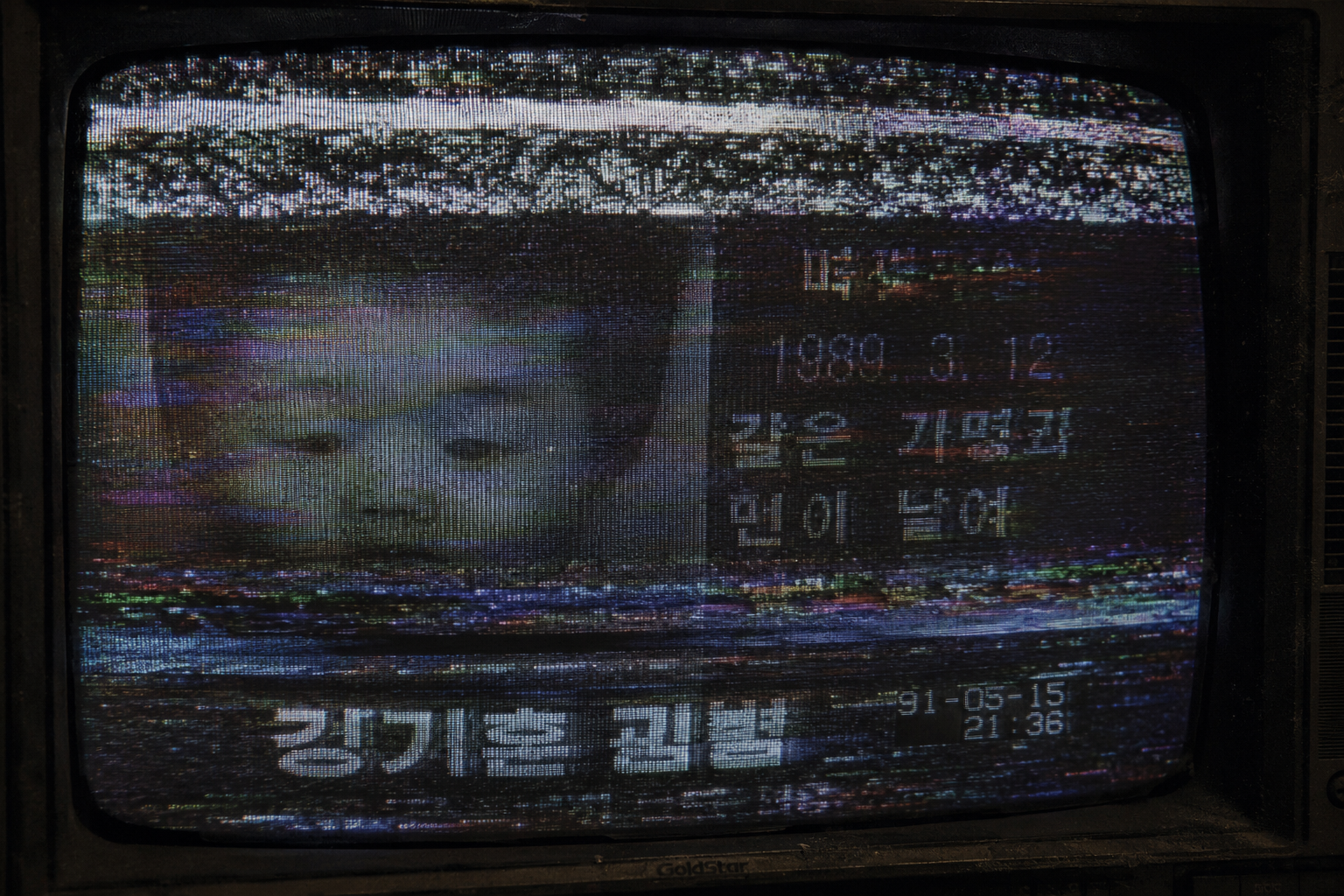 Macro close-up of a static-filled CRT monitor displaying a corrupted 1991 Korean missing child television broadcast with heavy VHS tracker lines.