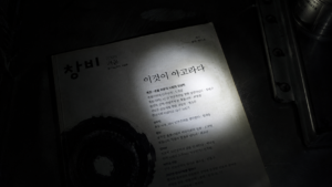 Labeled print edition of a 2008 Korean literary quarterly illuminated under a flashlight beam in a dark room.