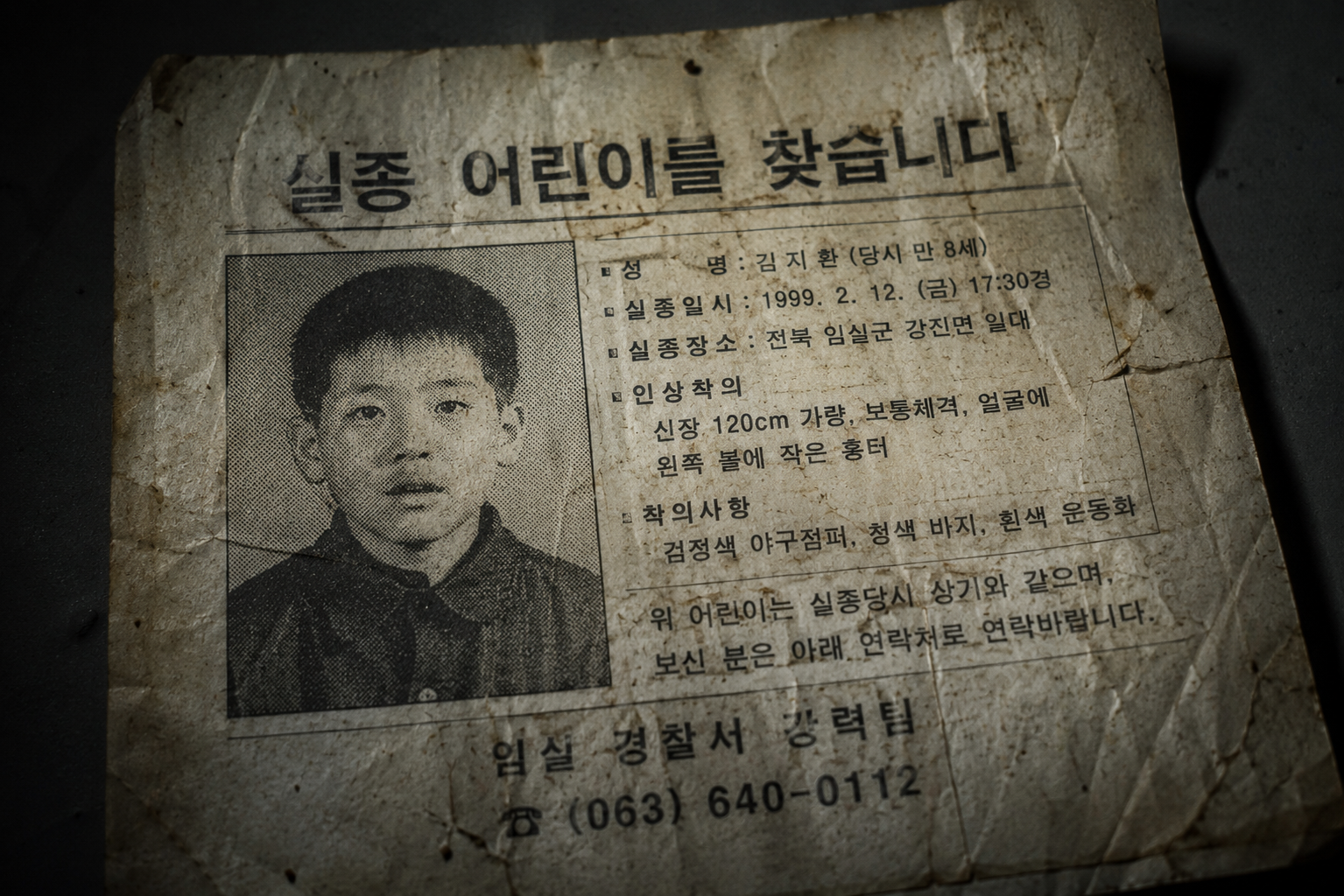 A macro close-up of a degraded vintage 1990s Korean document under a sharp cold light showing paper textures and ink bleed.