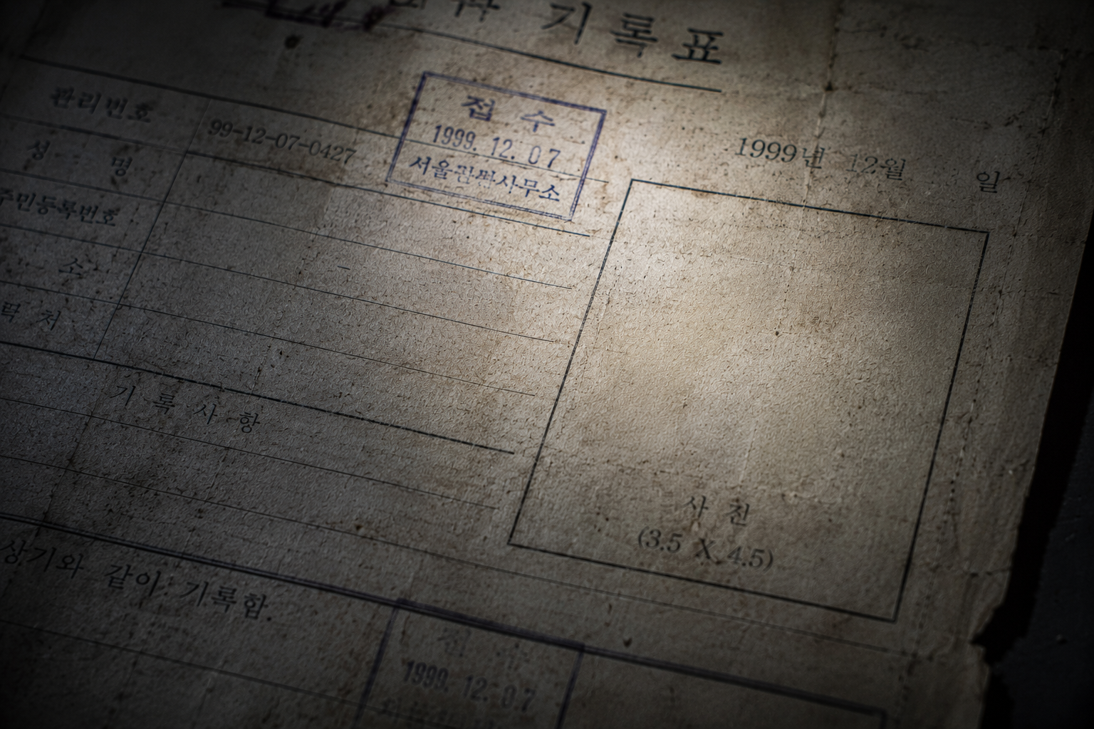 Close-up of a decayed 1999 South Korean missing persons police report with a missing profile photo.