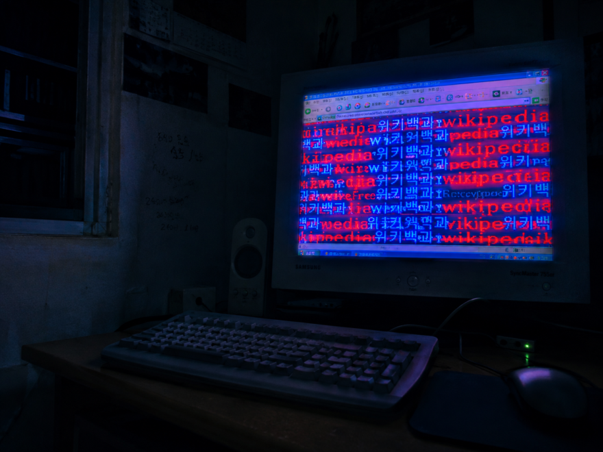 The 2011 Wikipedia Deletion Machine That Vanished Before It Was Traced An empty dark desk illuminated by a CRT monitor showing a corrupted wiki page filled with repeating neon flashing text strings, depicting the cold atmosphere of an unsolved digital investigation.