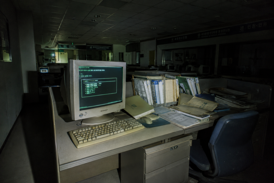 Flashlight lit forensic photograph of a glowing 2004 South Korean government computer terminal in a dark office.