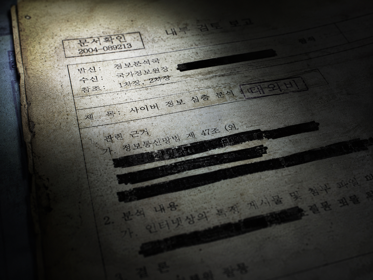 Macro close-up of a redacted and yellowed 2004 South Korean intelligence document under flashlight beams.